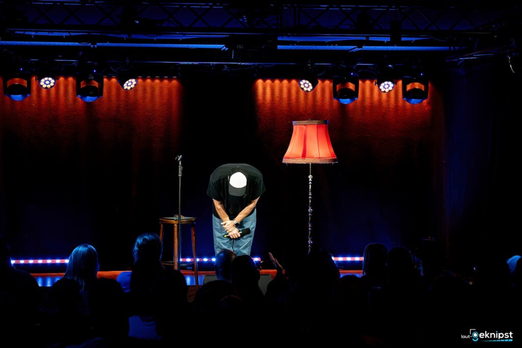 Comedian verbeugt sich auf der Bühne vor Publikum.