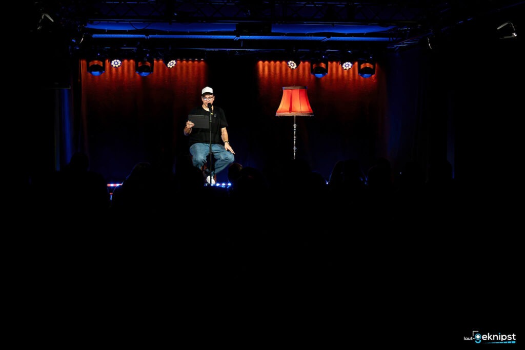 Person auf Bühne mit Stehlampe im Scheinwerferlicht.