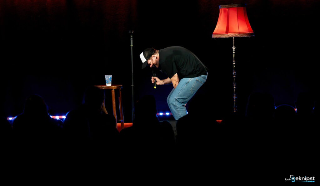 Mann bei Stand-Up-Comedy-Auftritt mit Mikrofon.