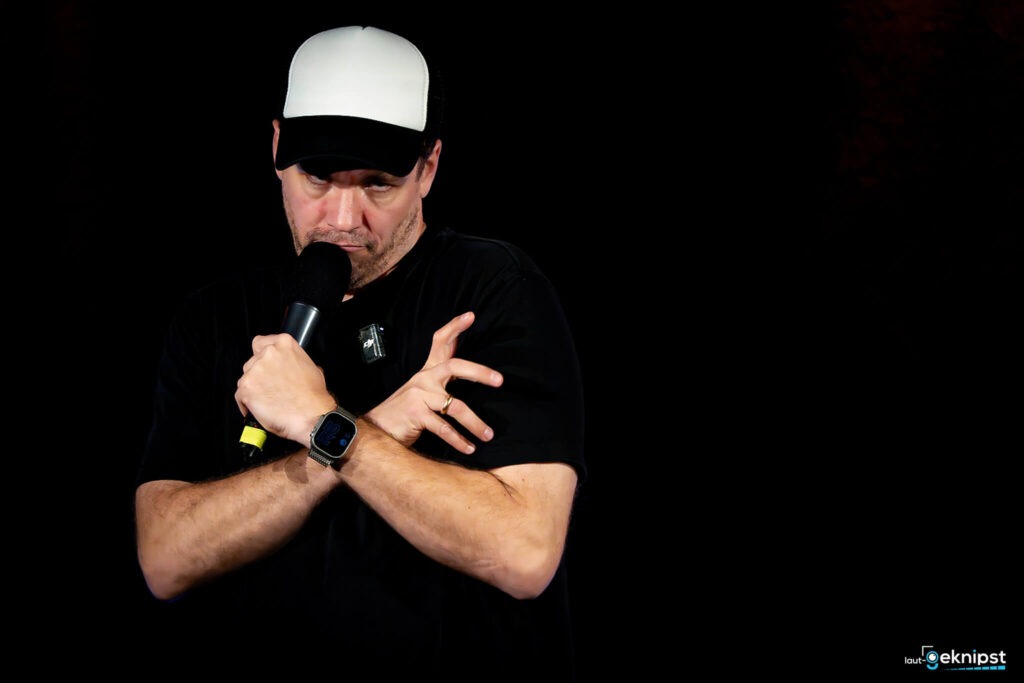 Mann mit Mikrofon auf schwarzem Hintergrund.