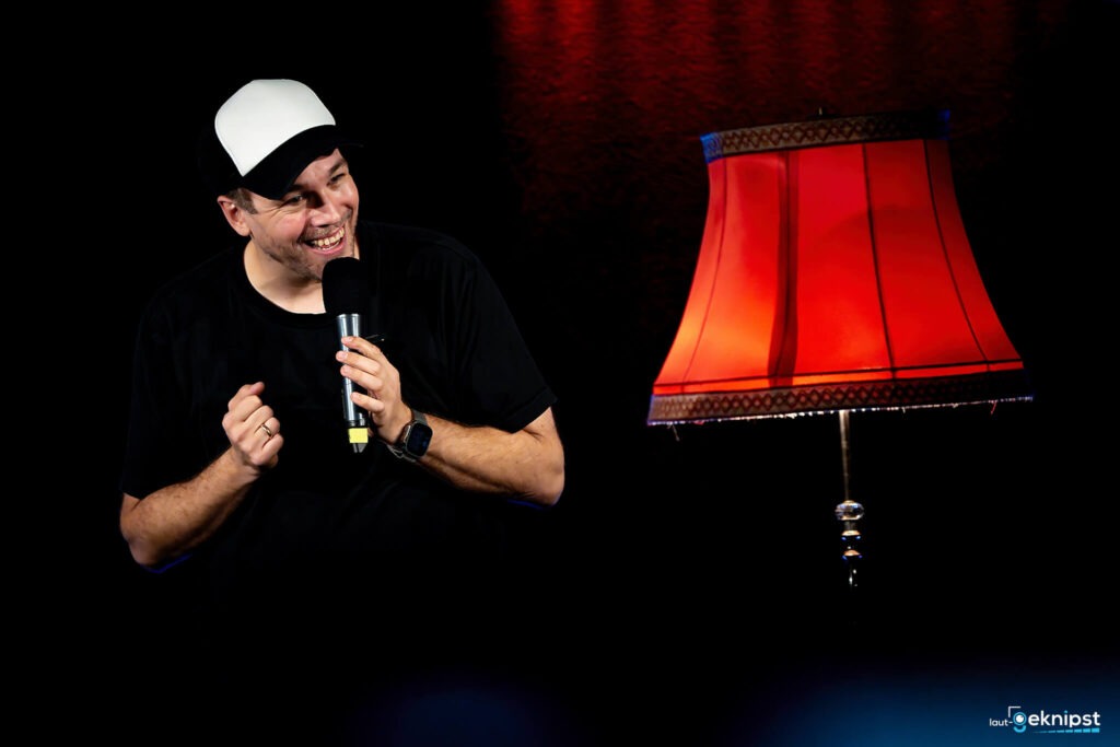 Mann mit Mikrofon neben roter Lampe