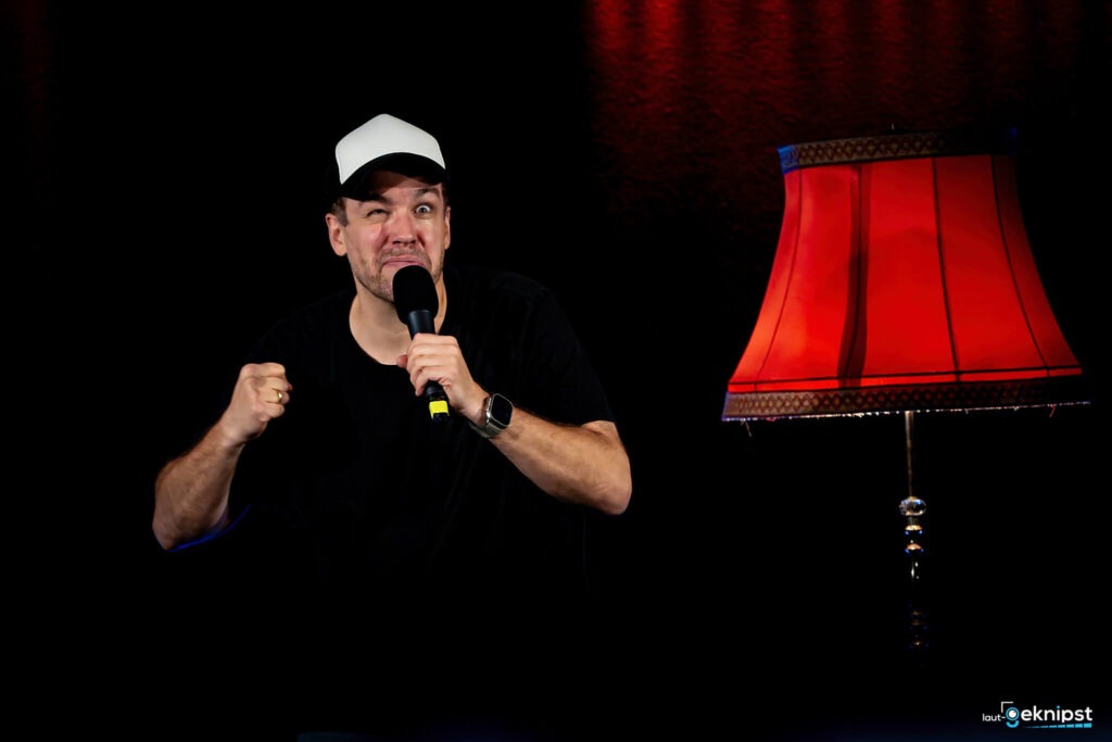 Mann mit Mikrofon neben roter Lampe