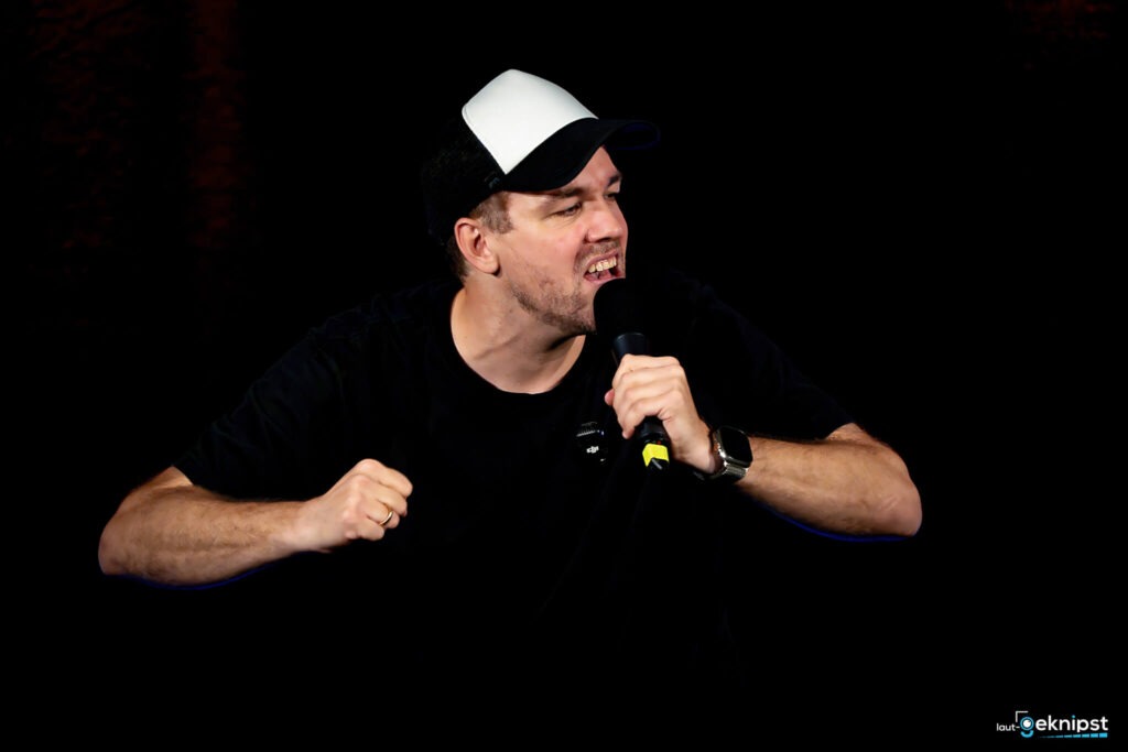 Mann hält Mikrofon und spricht energisch.