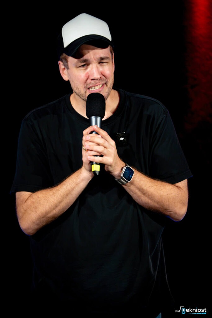 Mann mit Mikrofon und Baseballkappe auf Bühne