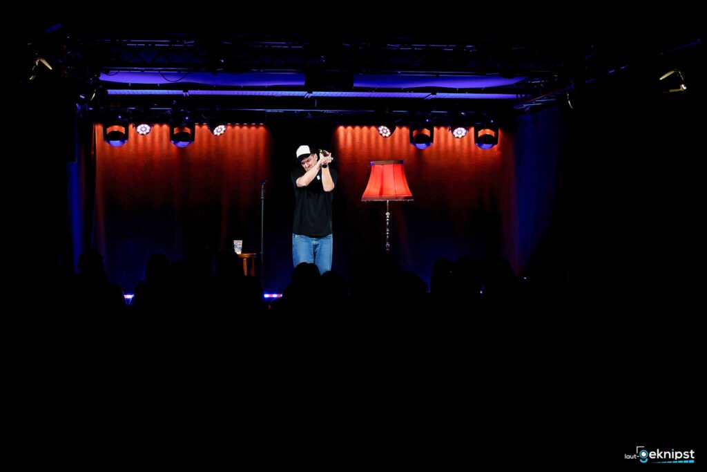 Bühnenauftritt mit rotem Lampenschirm und Publikum