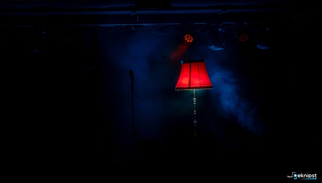 Rote Lampe und Mikrofon auf dunkler Bühne.