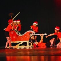 Kinder in Weihnachtskostümen mit Schlitten improvisieren