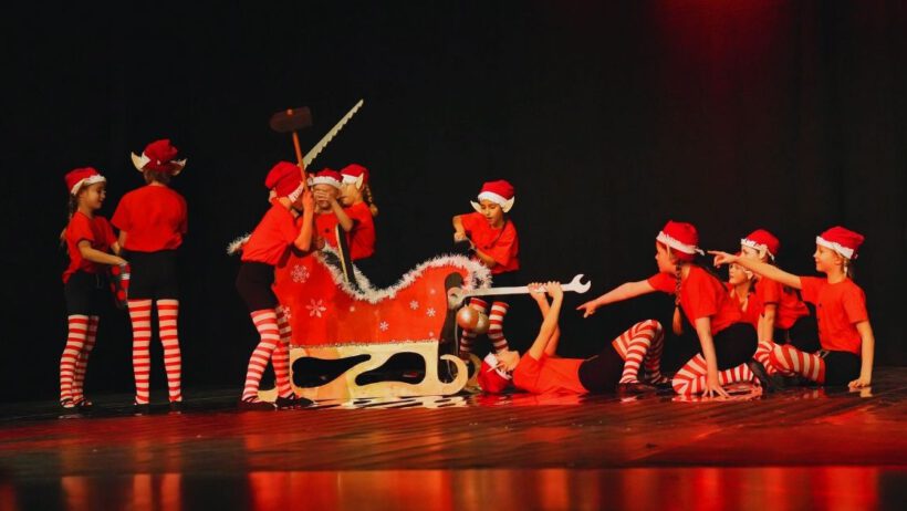 Kinder in Weihnachtskostümen mit Schlitten improvisieren