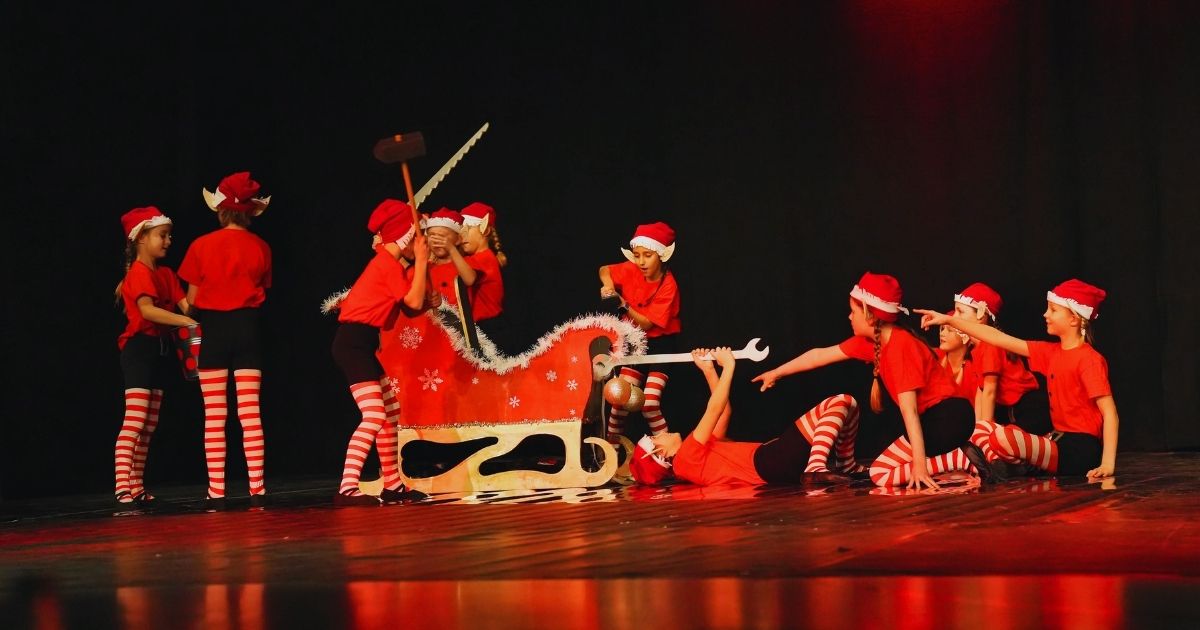 Kinder in Weihnachtskostümen mit Schlitten improvisieren
