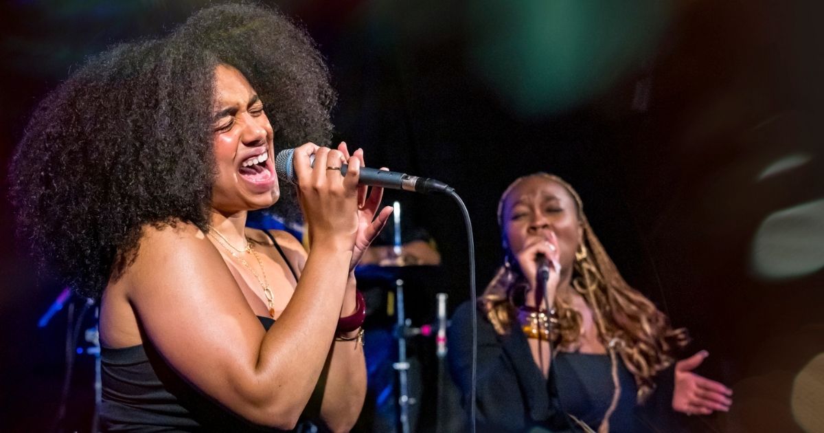 Zwei Frauen singen leidenschaftlich auf der Bühne.