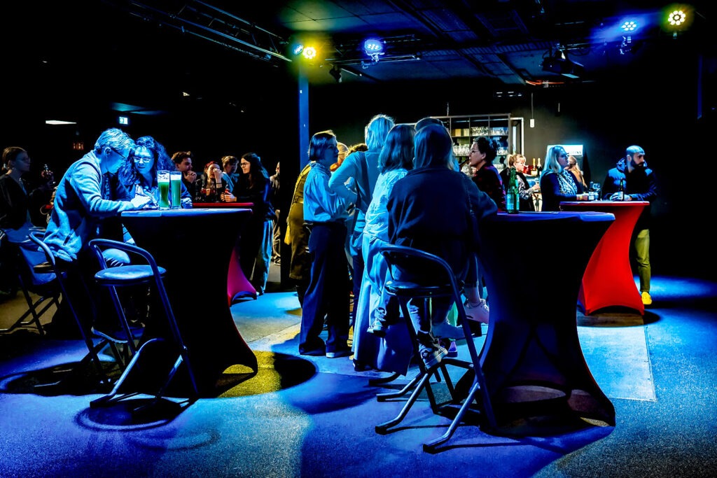 Menschen unterhalten sich bei einem Event an Stehtischen