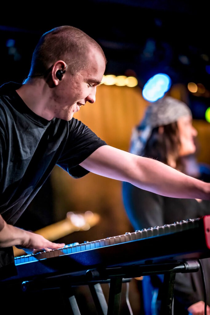 Mann spielt Keyboard auf der Bühne, bunt beleuchtet.