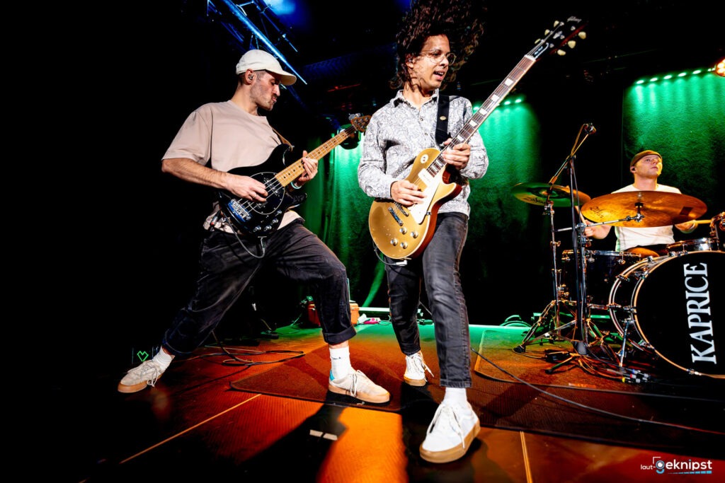 Band spielt Musik auf Bühne mit Gitarren und Schlagzeug.