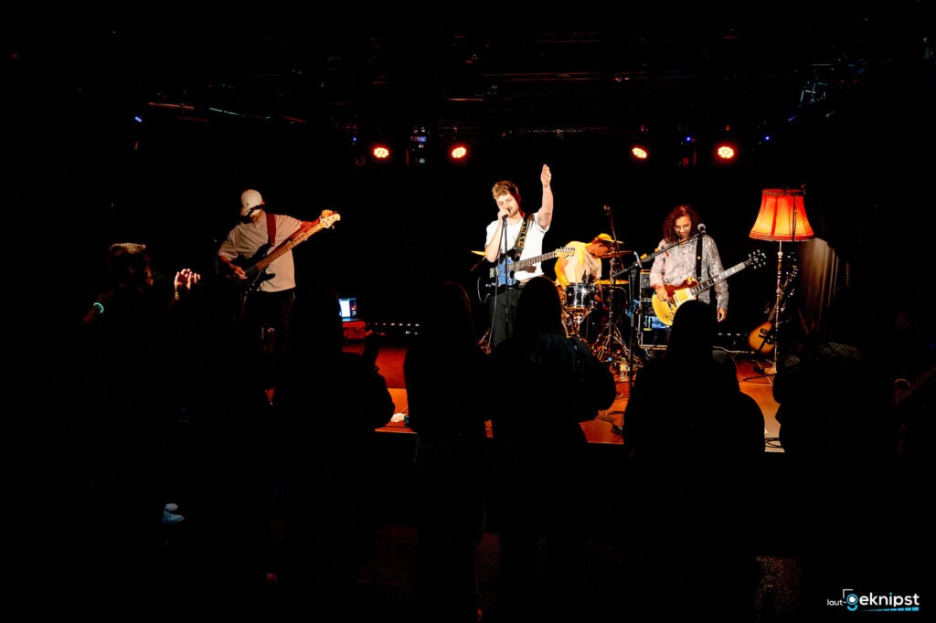 Live-Bandauftritt mit Publikum im dunklen Raum.