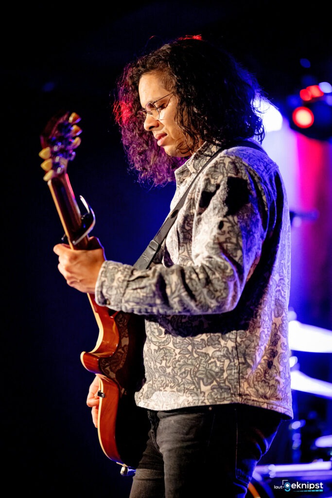Musiker spielt Gitarre bei Konzertauftritt.