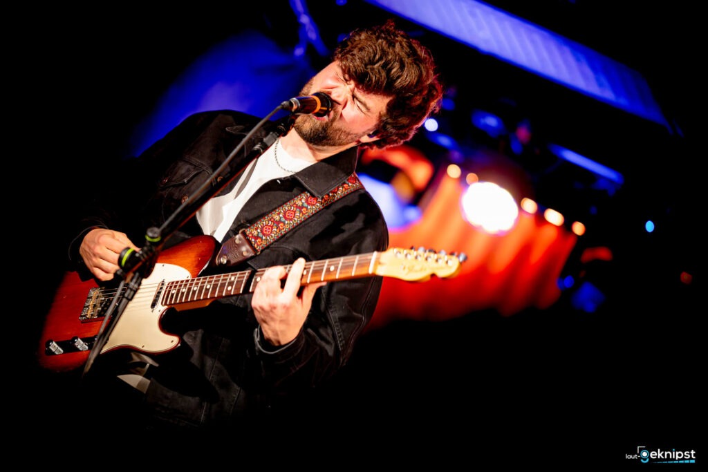 Mann spielt Gitarre auf der Bühne
